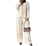 Person wearing a cream-colored outfit holding a leopard print handbag on a white background