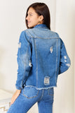 Woman wearing a blue denim jacket and jeans against a white background