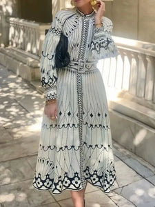 Woman in a black and white patterned dress sitting on stone steps.