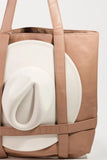 Brown tote bag with a white cushion inside on a light gray background