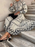 Woman in a black and white patterned dress sitting on stone steps.