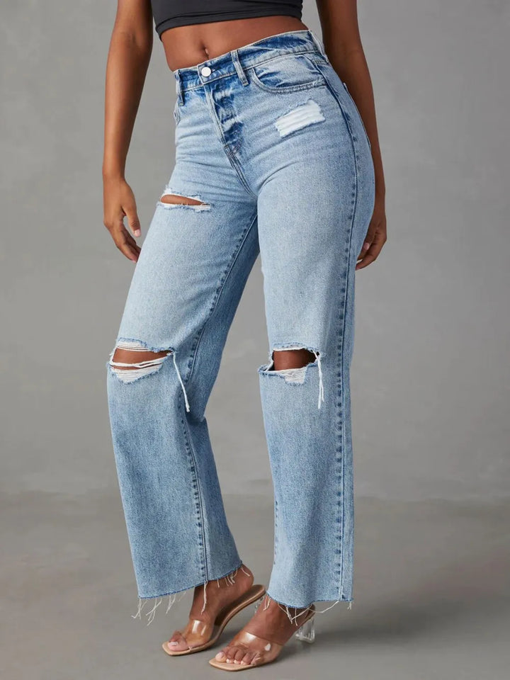Light blue jeans with distressing details worn by a person on a gray background