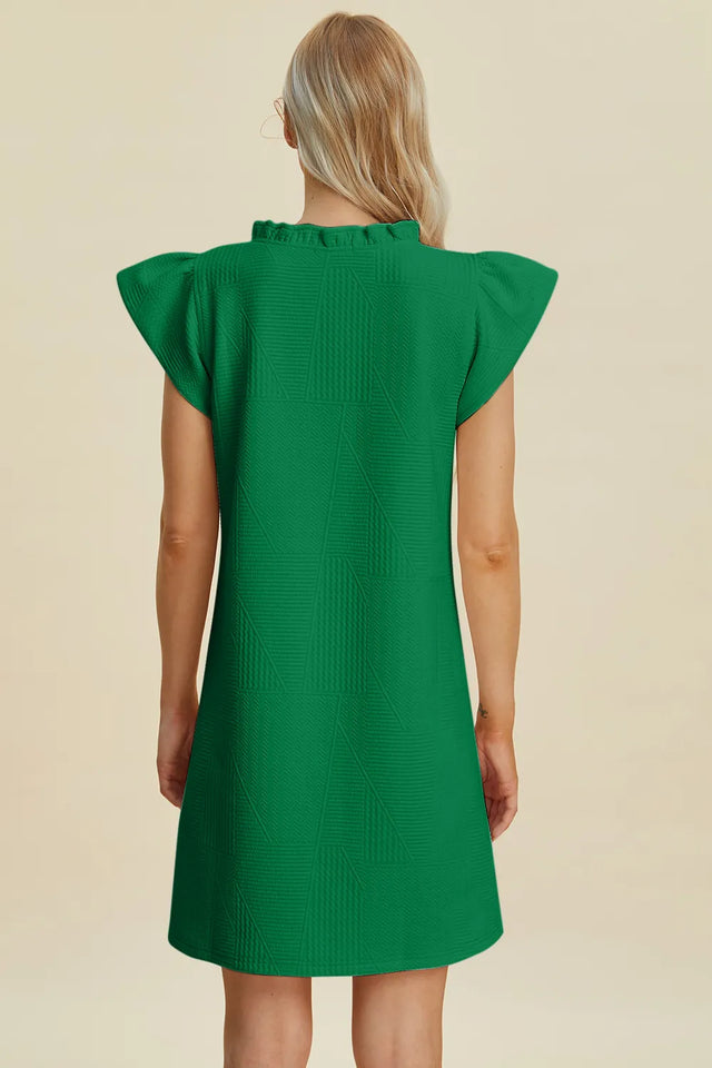 Green dress with ruffled sleeves on a beige background