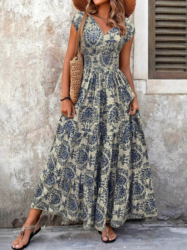 Woman wearing a floral dress standing against a textured wall.