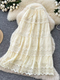 Cream-colored lace dress on a textured surface with flowers in the background