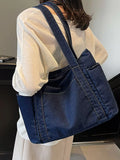 Person wearing a blue denim crossbody bag indoors