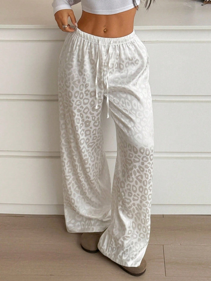 White pants with leopard print pattern worn by a person against a white wall.