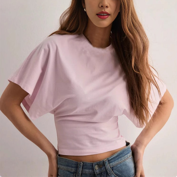 Woman wearing a light pink crop top and blue jeans against a plain background