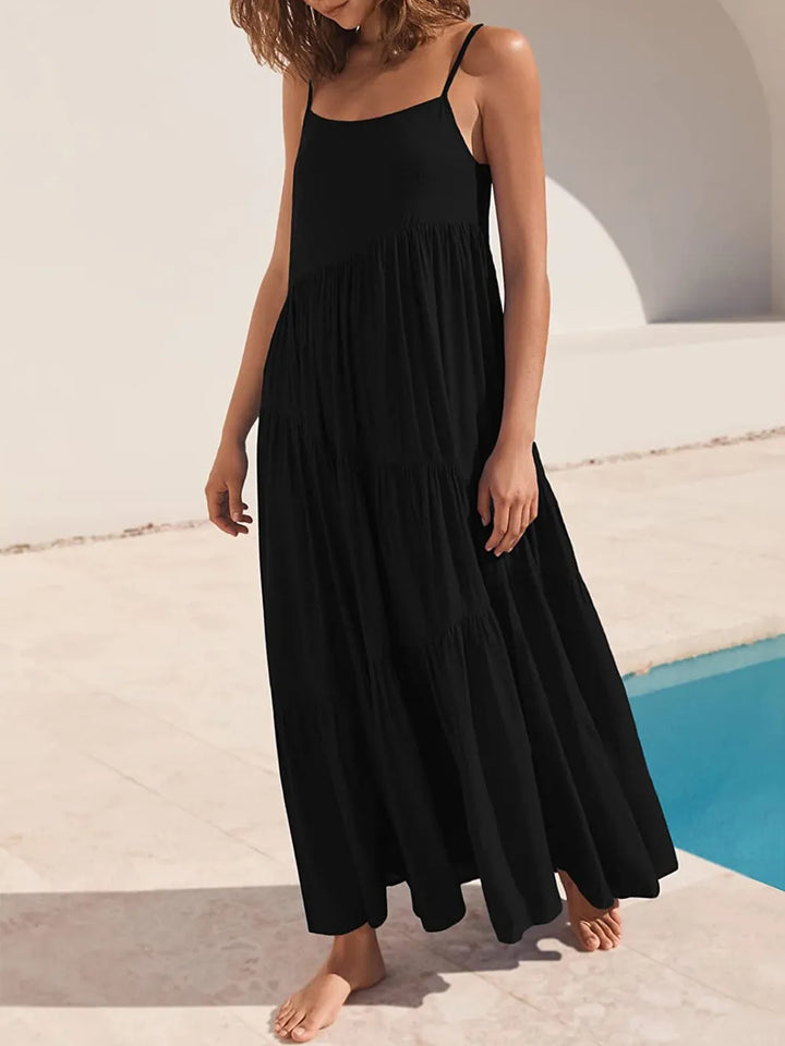 Woman wearing a black dress standing by a poolside.