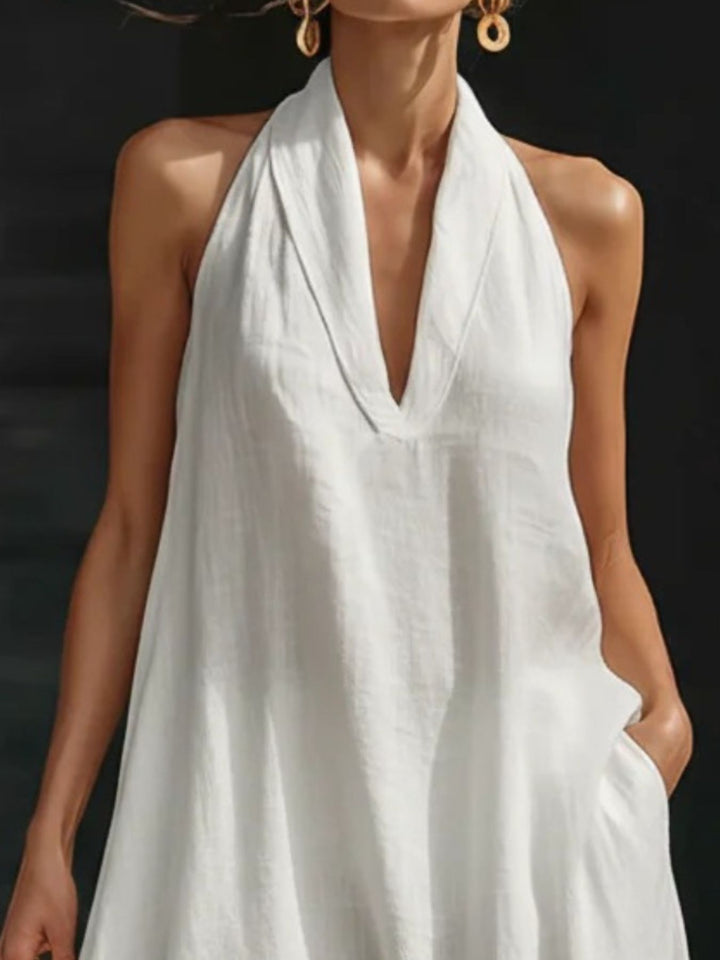 Woman wearing a white halter neck dress against a dark background