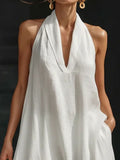 Woman wearing a white halter neck dress against a dark background