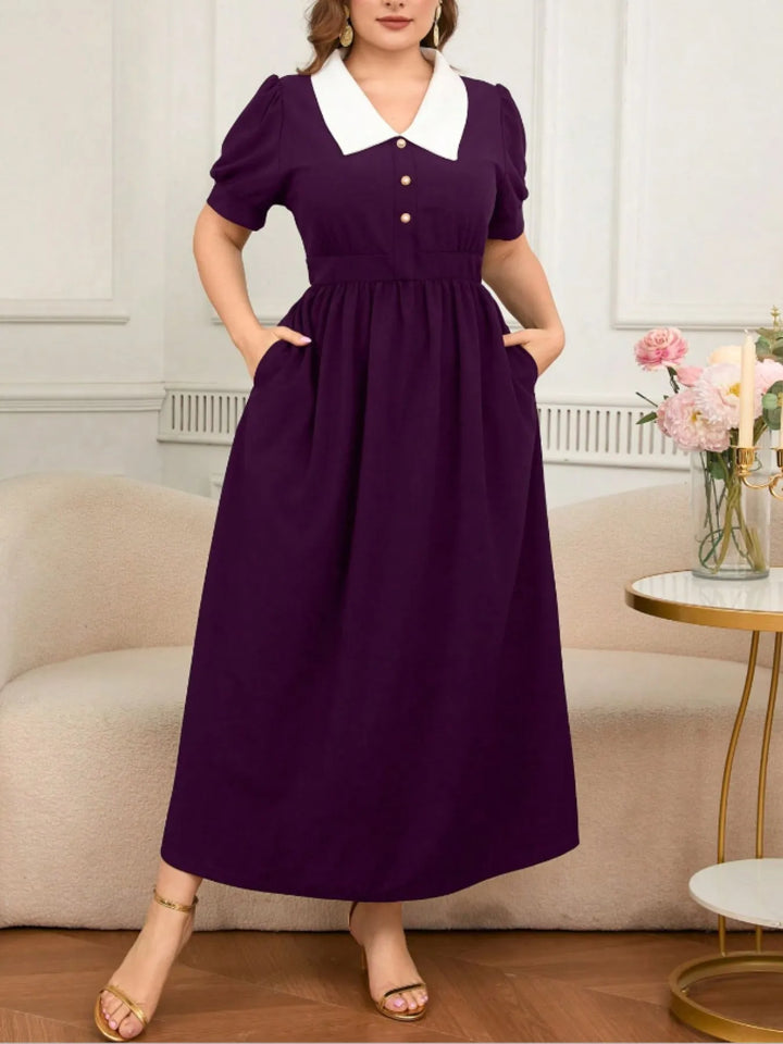 Woman wearing a purple dress with a white collar in a living room setting.