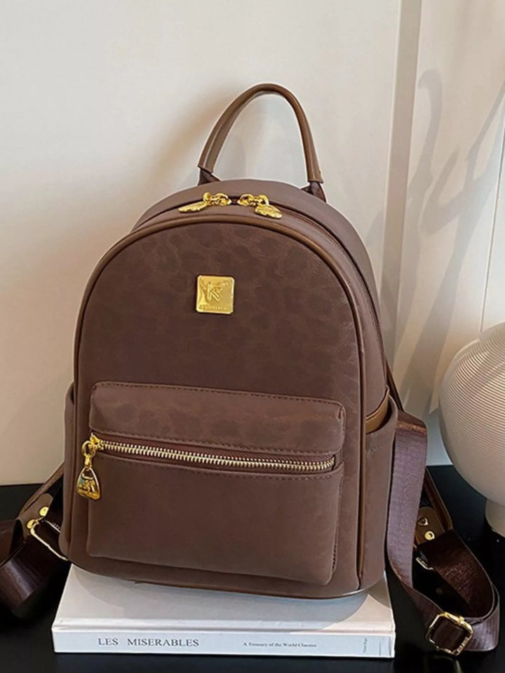 Brown backpack with gold accents on a white surface