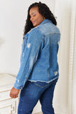 Person wearing a blue denim jacket and jeans in a white room