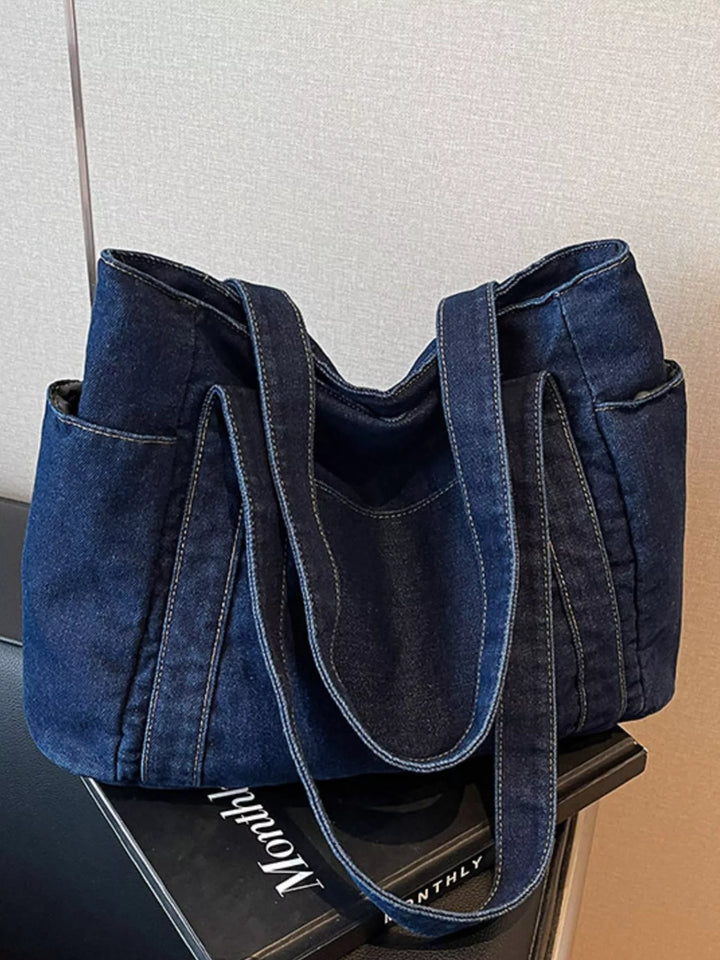 Blue denim handbag on a black surface with a blurred background