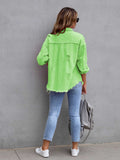 Person wearing a bright green distressed jacket and blue jeans against a gray wall.