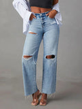 Ripped blue jeans worn by a person on a gray background