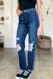Person wearing blue distressed jeans and black sneakers indoors.