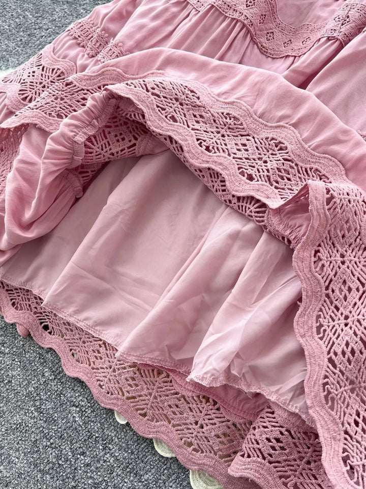 Close-up of a pink lace dress with ruffles on a gray surface