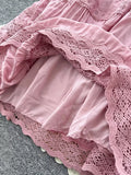 Close-up of a pink lace dress with ruffles on a gray surface
