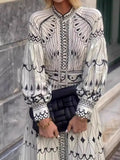 Person wearing a black and white patterned outfit with long sleeves, standing against a stone wall.