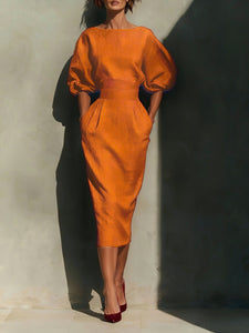 Orange dress with puff sleeves worn by a model against a neutral background