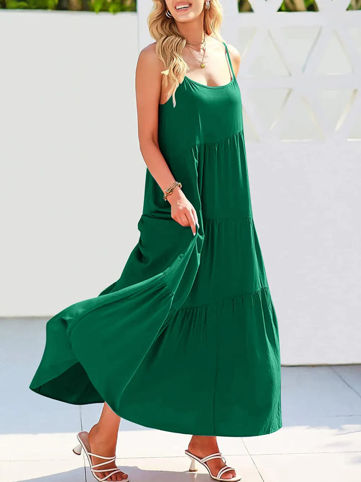 Woman wearing a green dress standing against a white wall.