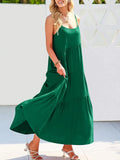 Woman wearing a green dress standing against a white wall.