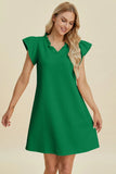 Woman wearing a green dress with ruffled sleeves on a beige background