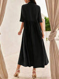 Woman wearing a black dress standing in front of beige curtains.