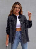 Woman wearing a black denim jacket over a white top and blue jeans on a gray background