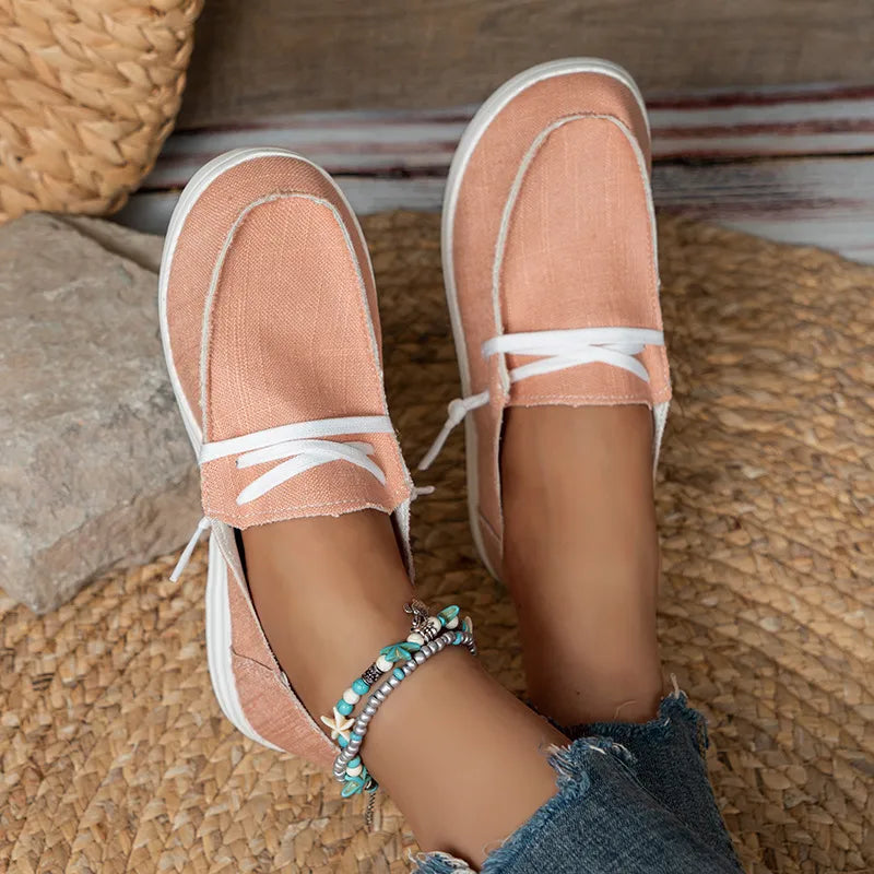 Pink loafers with white laces worn on a woven mat