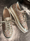 Pair of glittery sneakers on a textured surface