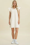 Woman wearing a white dress with ruffled sleeves on a beige background