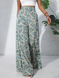 Person wearing tropical leaf-patterned pants with a white top against a gray background