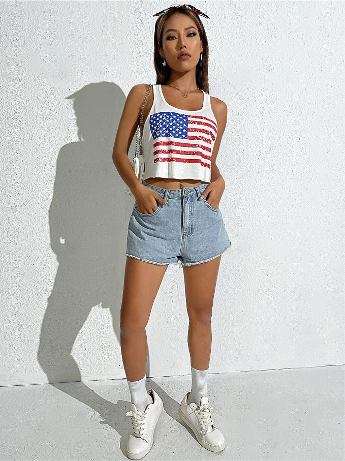 Person wearing an American flag tank top and denim shorts against a white wall.