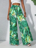 Person wearing green tropical leaf print pants against a gray background