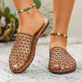 Brown woven sandals worn with anklets on a textured surface.