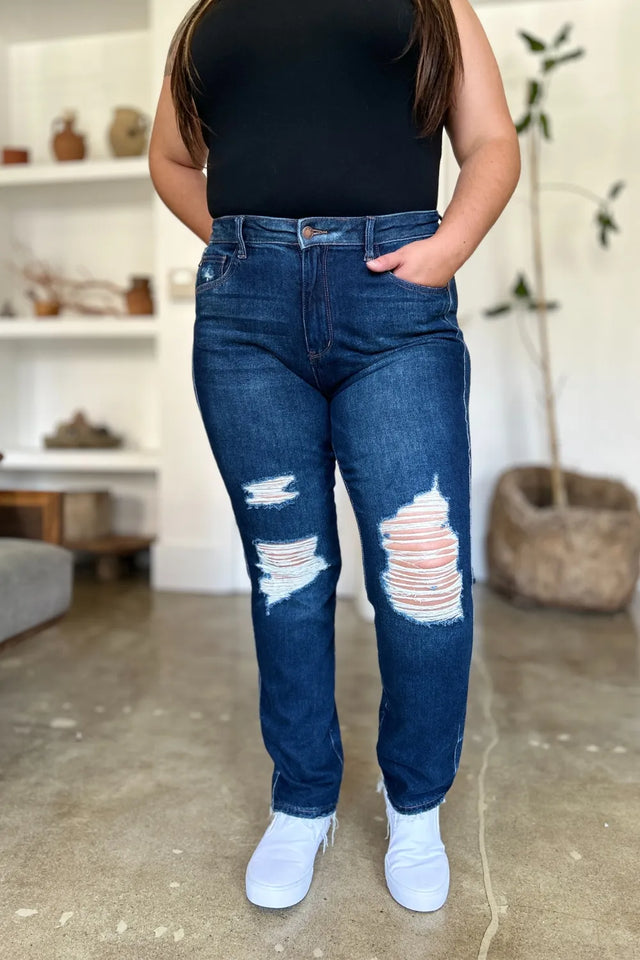 Person wearing blue distressed jeans and a black top indoors.