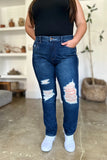 Person wearing blue distressed jeans and a black top indoors.