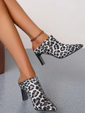 Leopard print ankle boots worn by a person on a neutral background