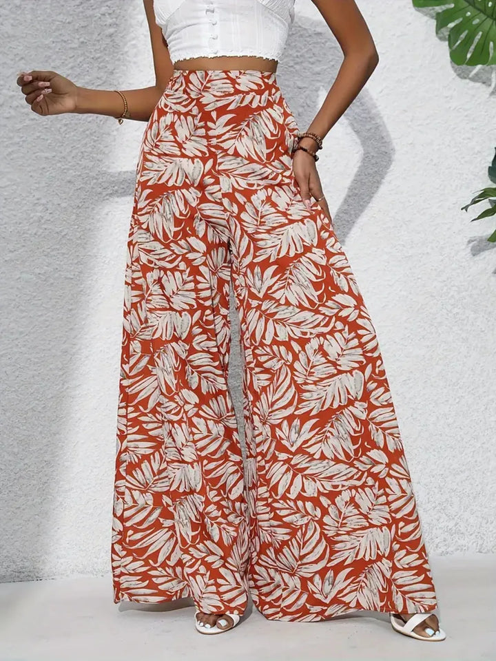 Person wearing red and white leaf-patterned wide-leg pants on a light gray background