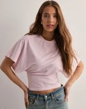 Woman wearing a light pink crop top and blue jeans against a plain background