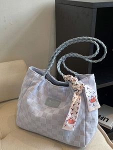 Person holding a woven handbag with a matching pouch on a beige couch