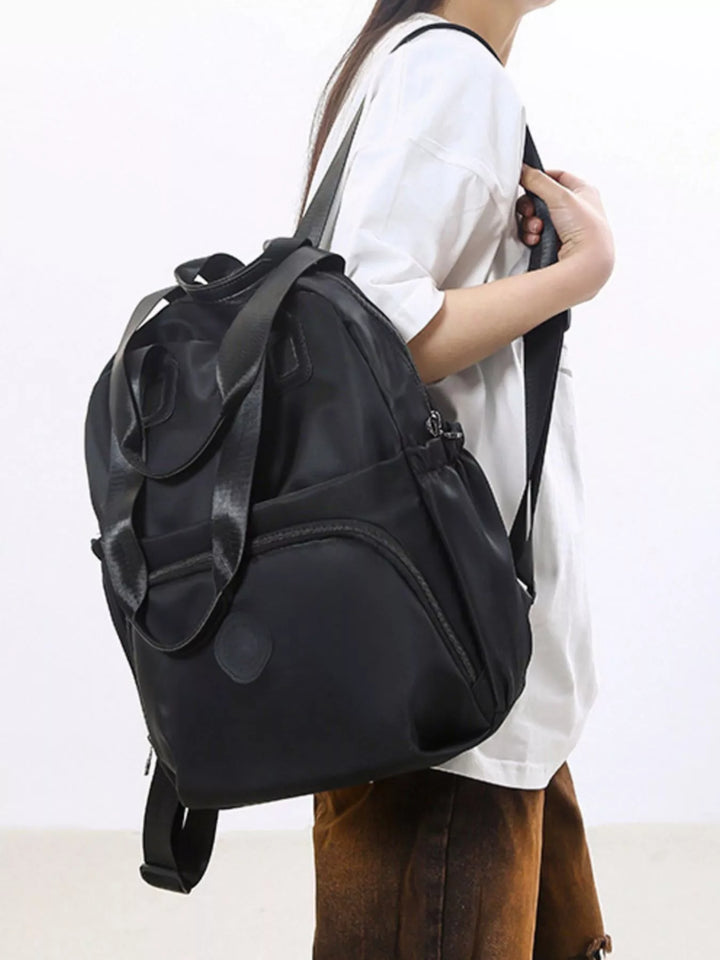 Person wearing a black backpack on a plain background