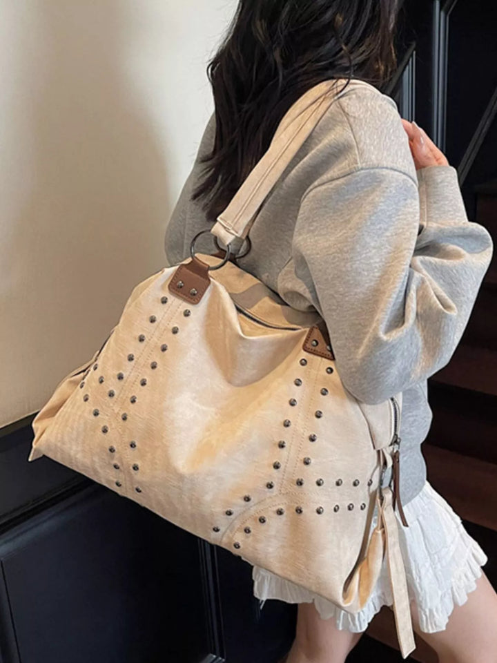 Person wearing a beige tote bag with studded details