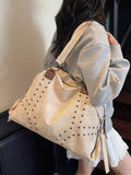 Person wearing a beige tote bag with studded details