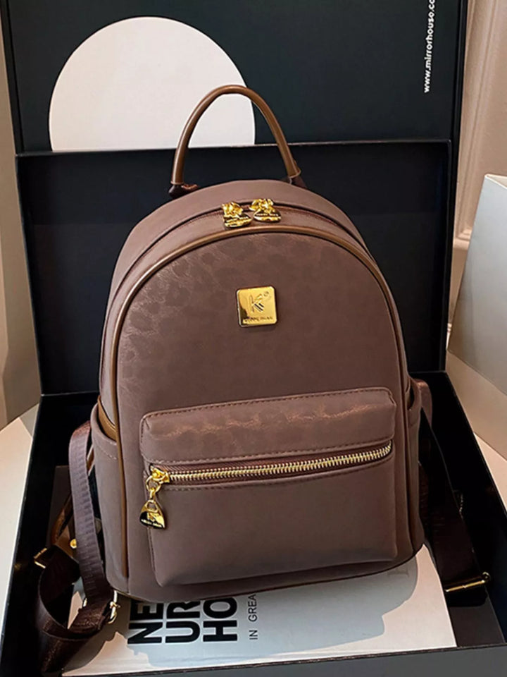 Brown backpack with gold accents on a white surface