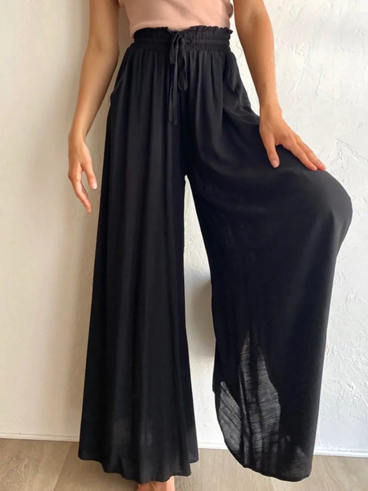Person wearing black wide-leg pants against a neutral background