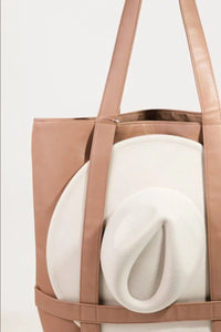 Brown tote bag with a white cushion inside on a light gray background